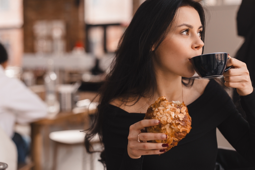 Ceșcă de cafea lângă o farfurie cu portocale și mâncare picantă