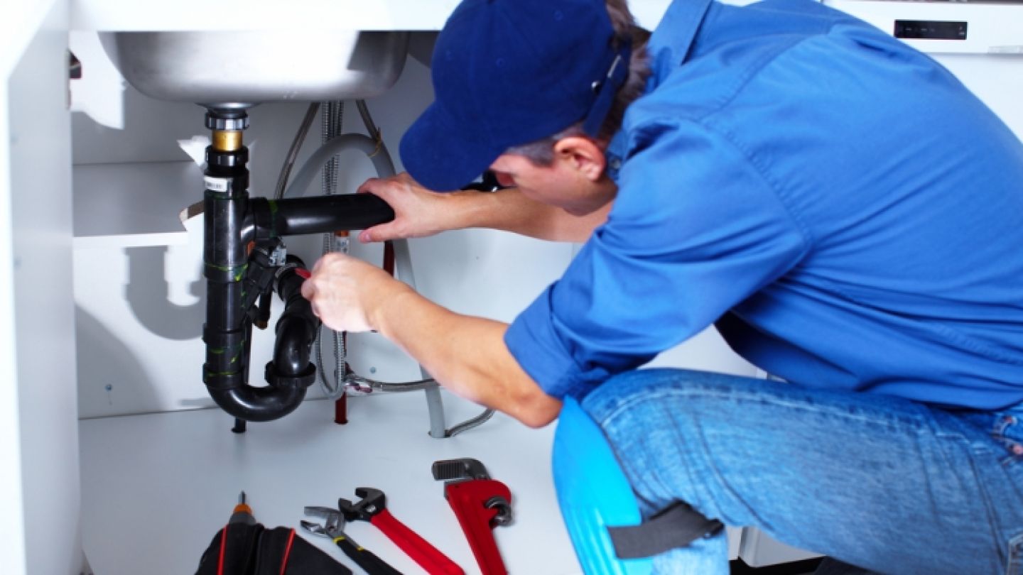Instalator lucrând la o instalație sanitară