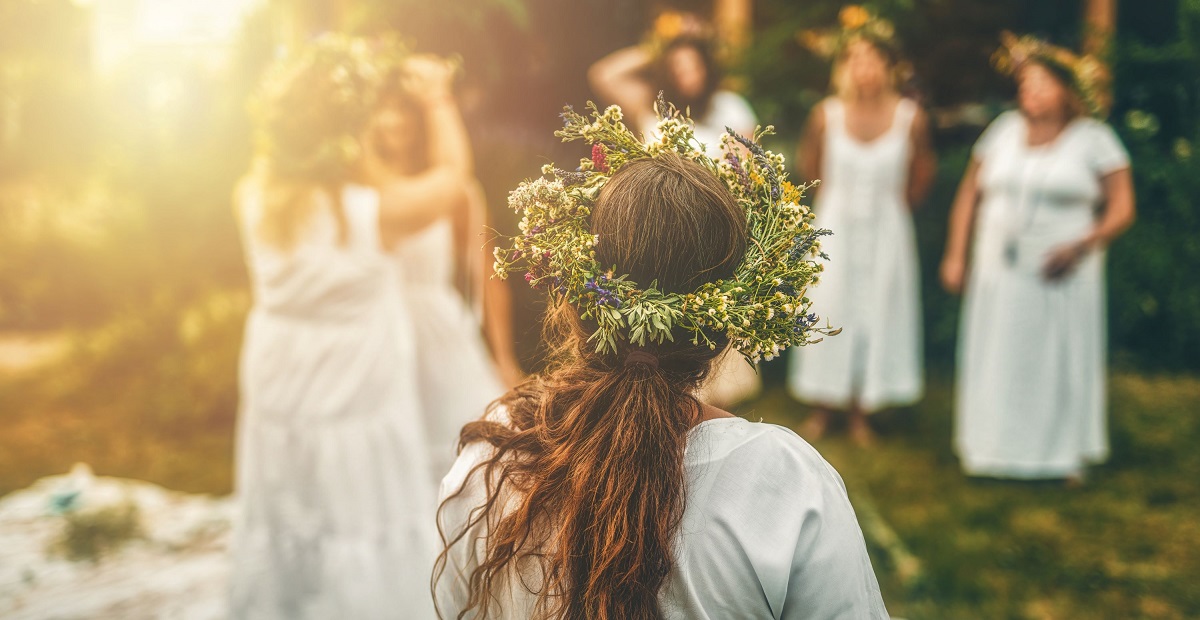 Fete tinere îmbrăcate în costume tradiționale românești, ținând flori de sânziene, într-un peisaj de vară, noaptea.