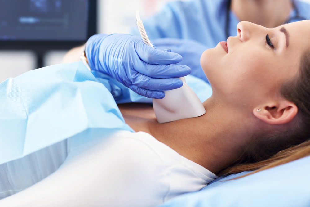 Medic examinând gâtul unui pacient pentru depistarea nodulilor tiroidieni