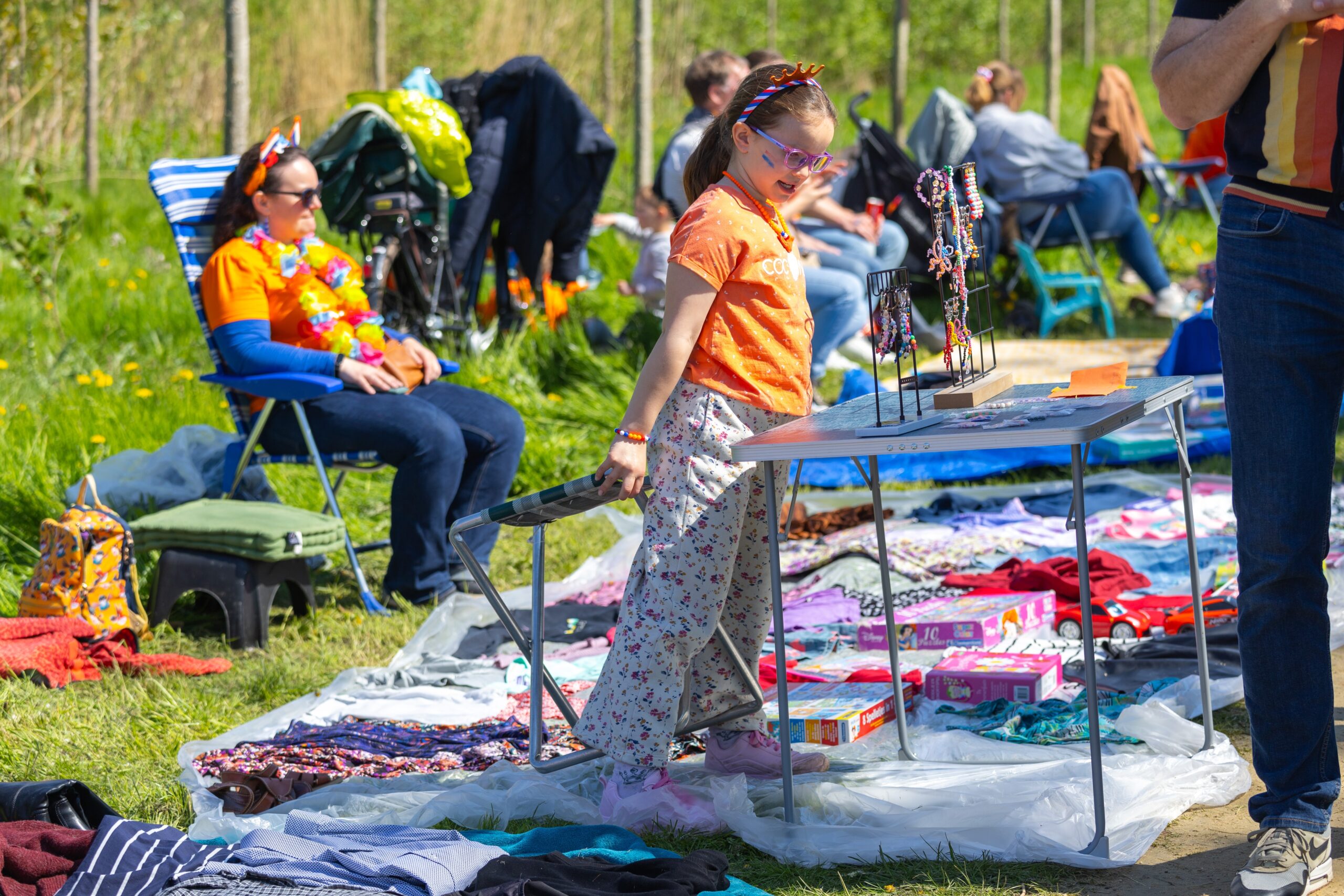 Copii olandezi participând la Avondvierdaagse, plimbându-se pe o stradă cu flori și medalii