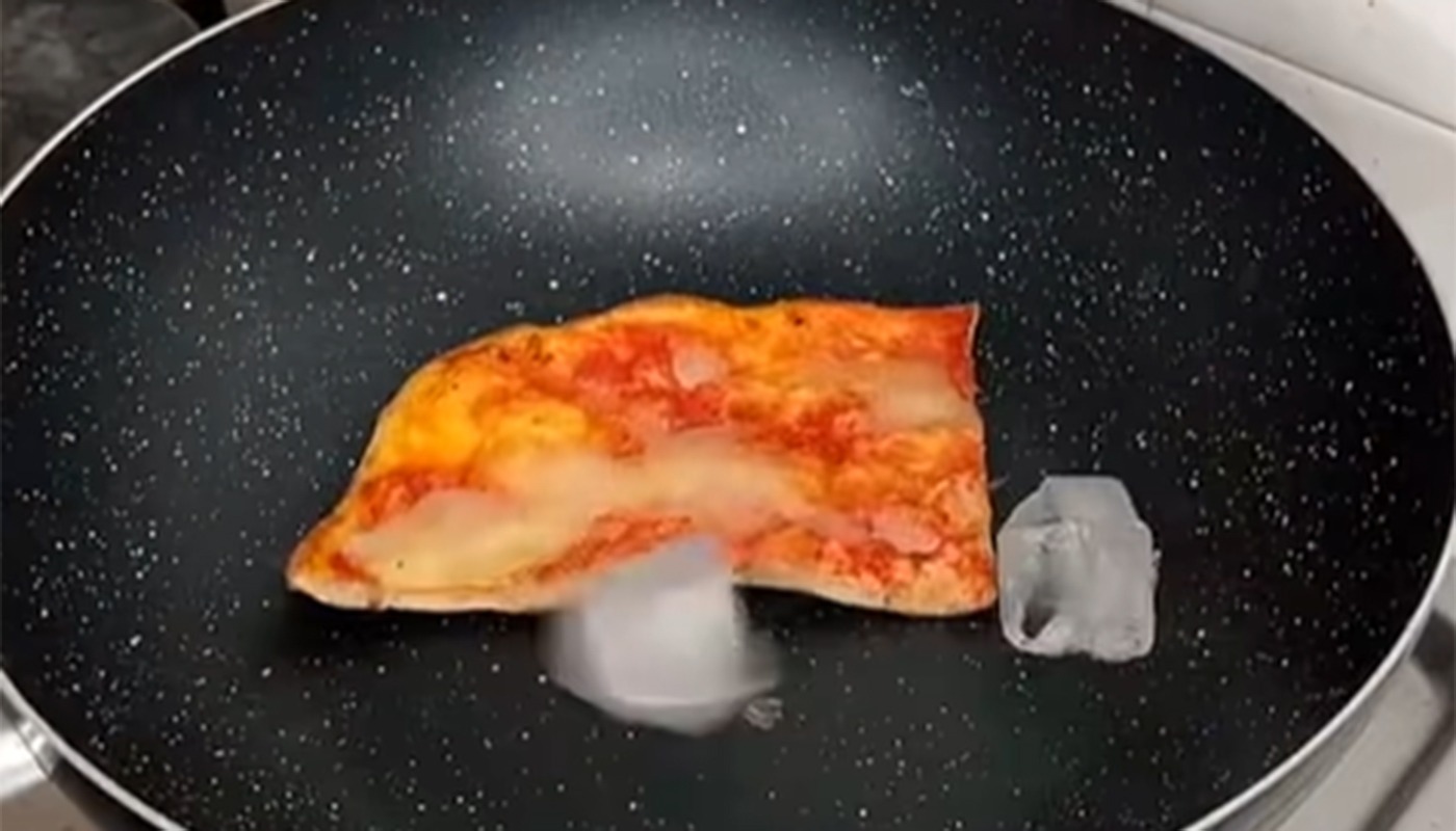 Pizza proaspăt reîncălzită într-o tigaie cu cuburi de gheață