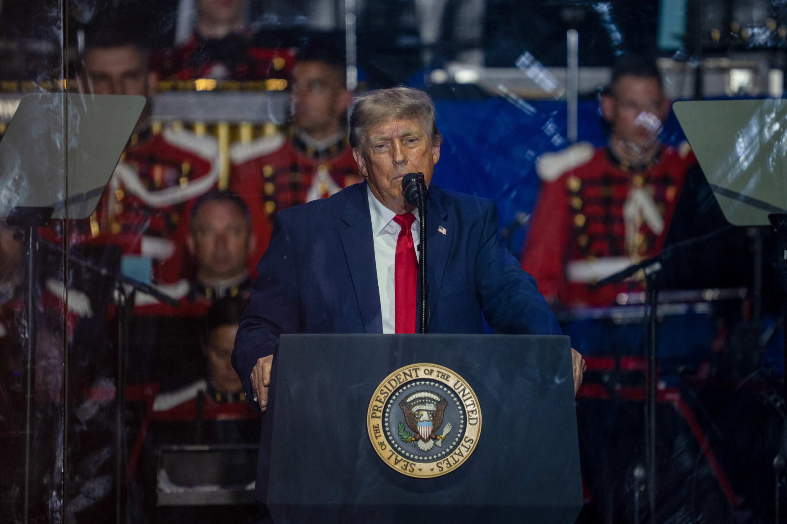 Președintele Donald Trump ține un discurs pe National Mall, în fața unei mulțimi numeroase, cu avioane de luptă survolând cerul.