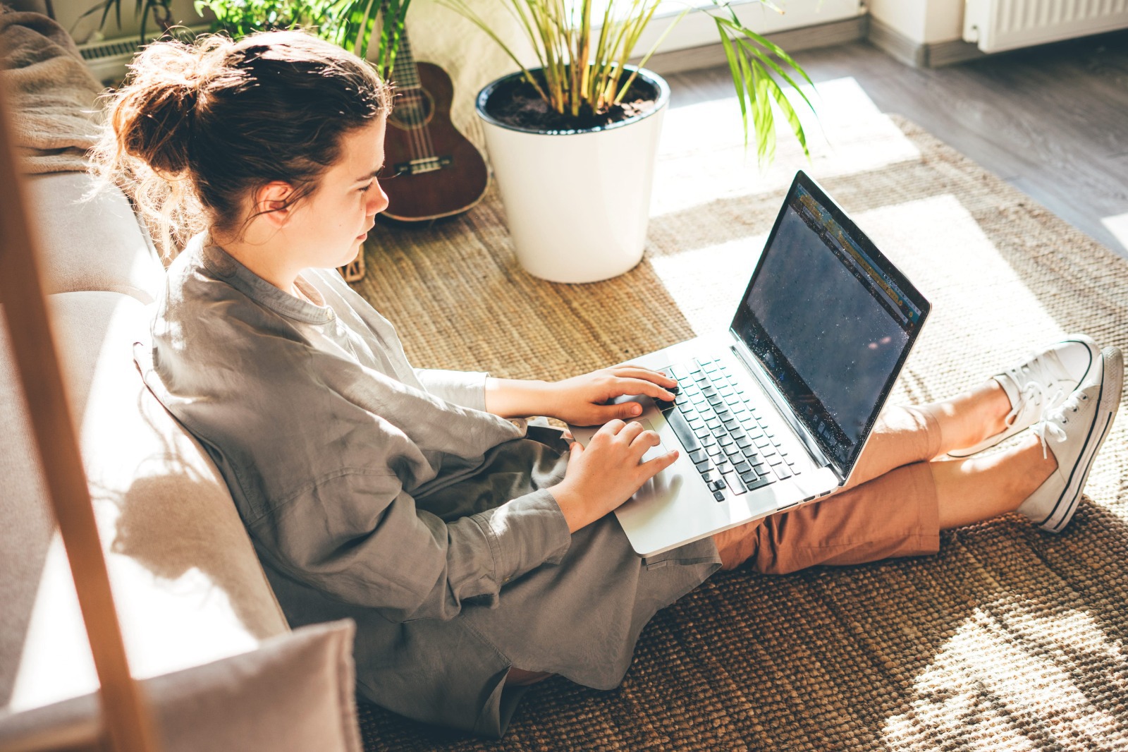 Tânără care lucrează de acasă la laptop