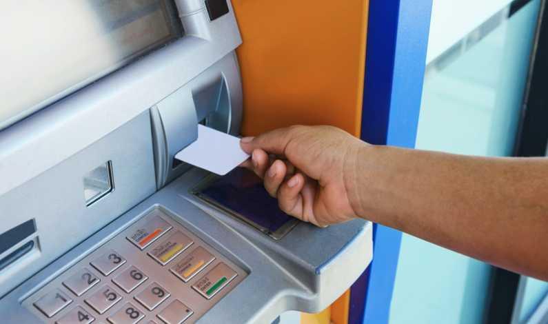 Turiști la un bancomat în străinătate, cu monede și bancnote în mână